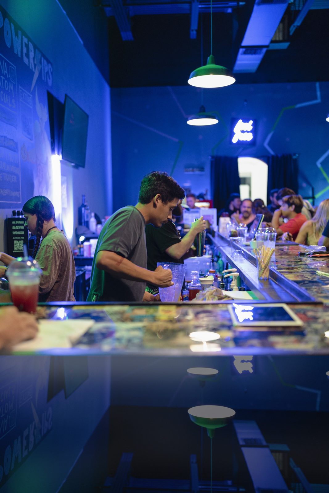 Bartender mixing a kava drink behind the comic-panel bar top at Komic Kava in Boca Raton